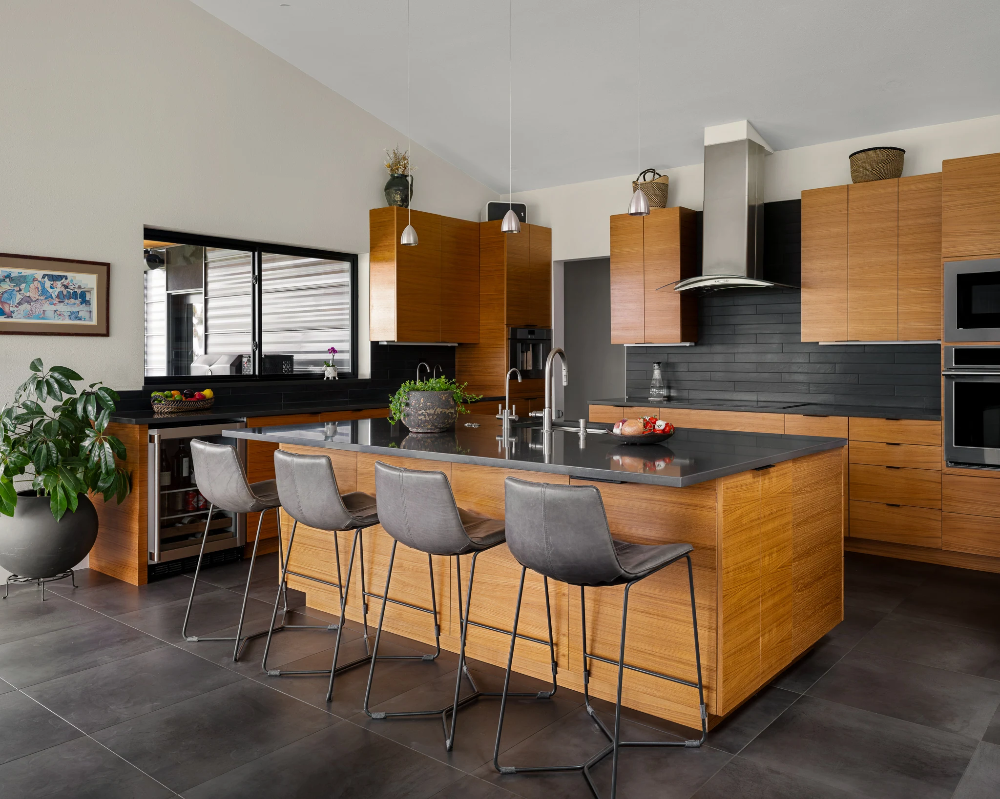 Kitchen with warm wood cabinetry and a black stone island — interior design photography Bozeman Montana, Living Places Design Studio